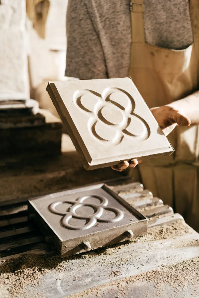 Hand hält Steinfliese mit Muster in Werkstatt.