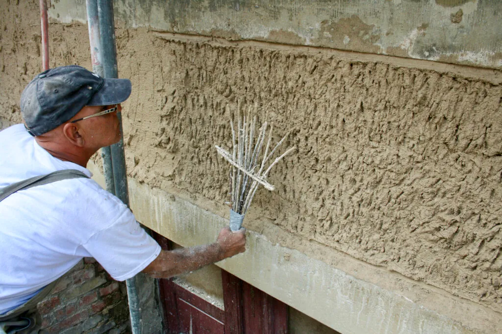 Arbeiter verputzt Wand mit Werkzeug.