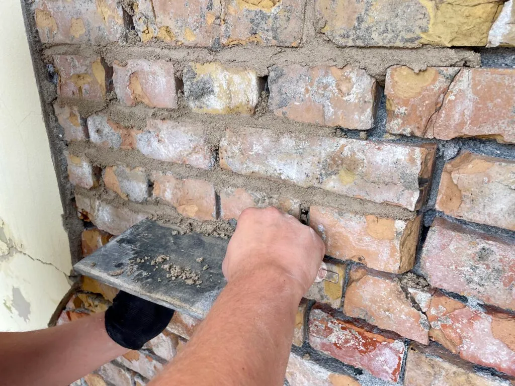 Mauerwerk wird ausgebessert mit Fugenmörtel.